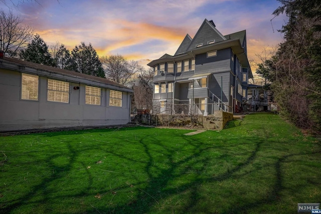 back house at dusk featuring a yard