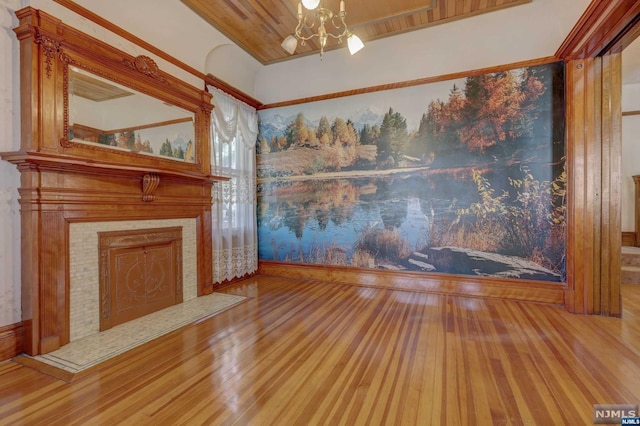 unfurnished living room featuring a tile fireplace, wood-type flooring, and an inviting chandelier