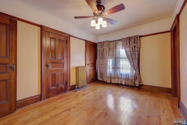 unfurnished bedroom with light wood-type flooring, radiator, and ceiling fan