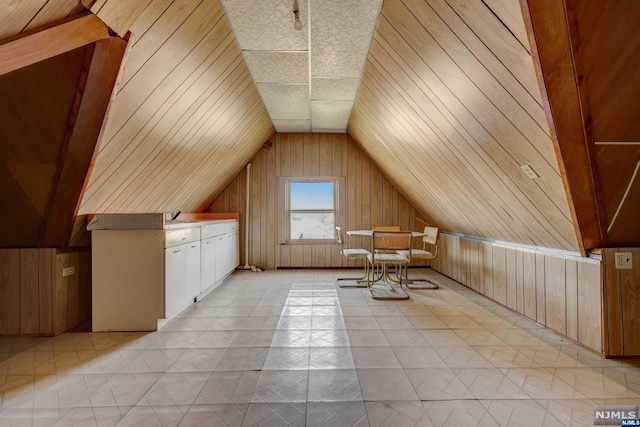 additional living space featuring lofted ceiling and wooden walls