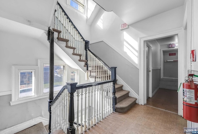 stairway featuring a wealth of natural light and parquet floors