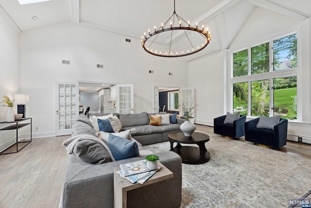 living room with french doors, light wood-type flooring, high vaulted ceiling, beamed ceiling, and a chandelier