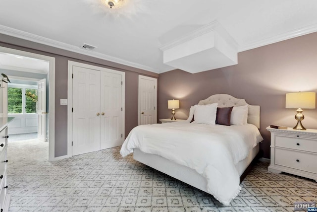 carpeted bedroom featuring two closets and ornamental molding