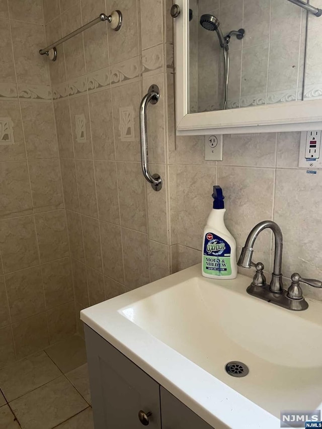 bathroom with tile patterned floors, vanity, tile walls, and tasteful backsplash