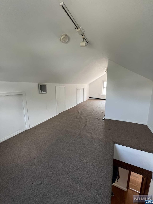 bonus room with lofted ceiling and dark colored carpet