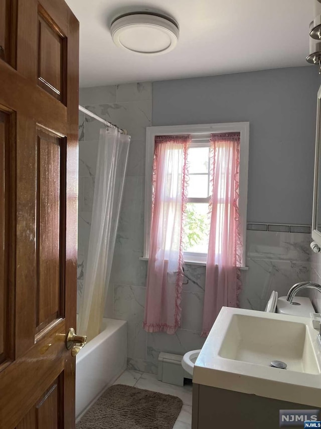 bathroom with vanity, shower / bathtub combination with curtain, and tile walls