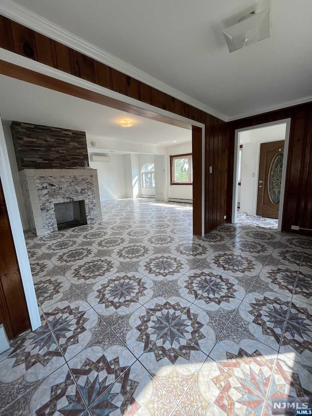 unfurnished living room with a stone fireplace, wooden walls, and ornamental molding