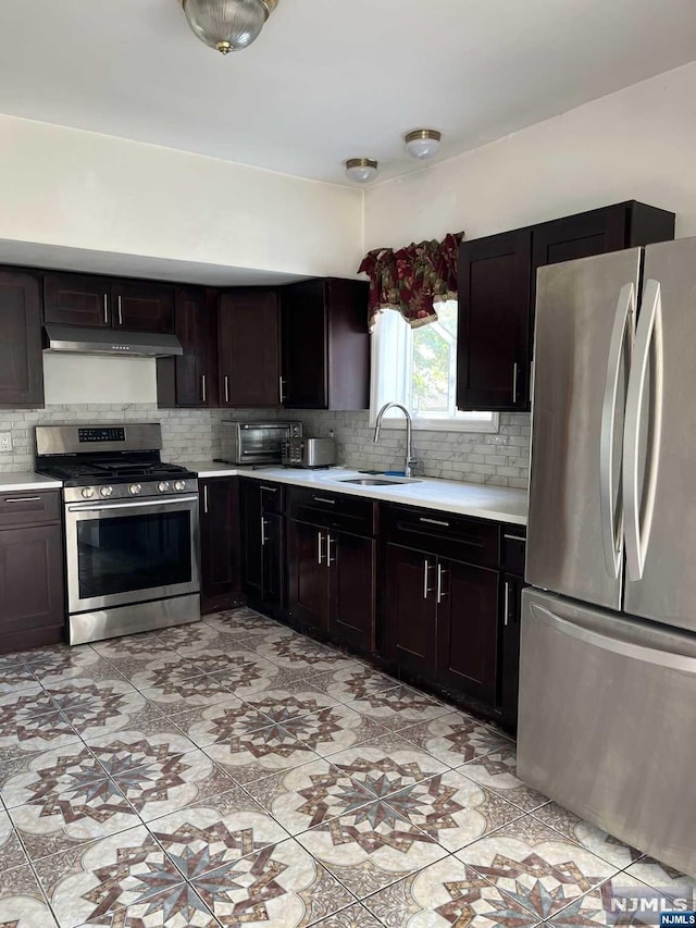 kitchen with backsplash, sink, light tile patterned floors, dark brown cabinets, and stainless steel appliances