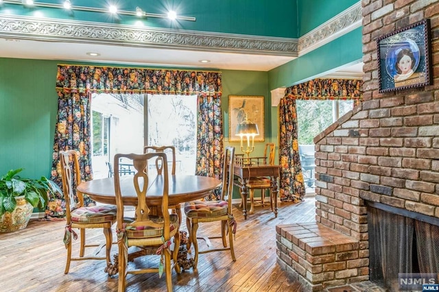 dining room with wood-type flooring and a brick fireplace