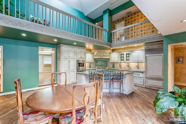 dining room with a high ceiling and light hardwood / wood-style floors