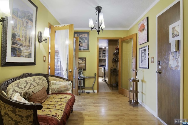 sitting room with a textured ceiling, a chandelier, crown molding, and light hardwood / wood-style flooring