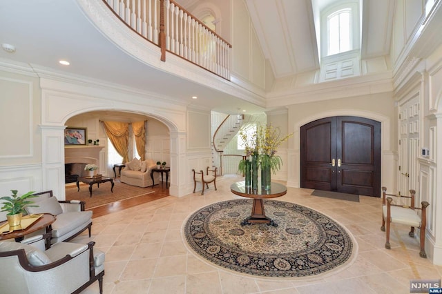 foyer with ornate columns, a high ceiling, and ornamental molding