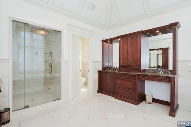 bathroom with toilet, an enclosed shower, tile walls, and vanity