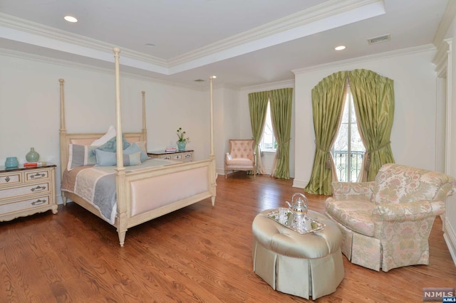 bedroom featuring a tray ceiling, crown molding, and hardwood / wood-style floors