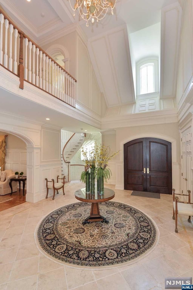 foyer entrance with ornamental molding, a high ceiling, and an inviting chandelier