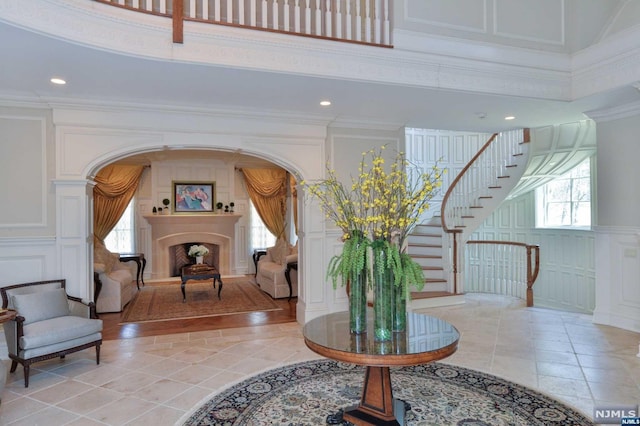 entryway with crown molding, light tile patterned floors, and a high ceiling