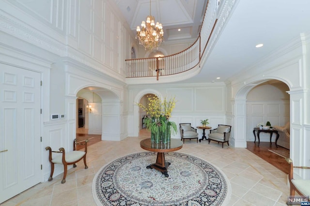 interior space featuring a notable chandelier, ornate columns, ornamental molding, and a high ceiling