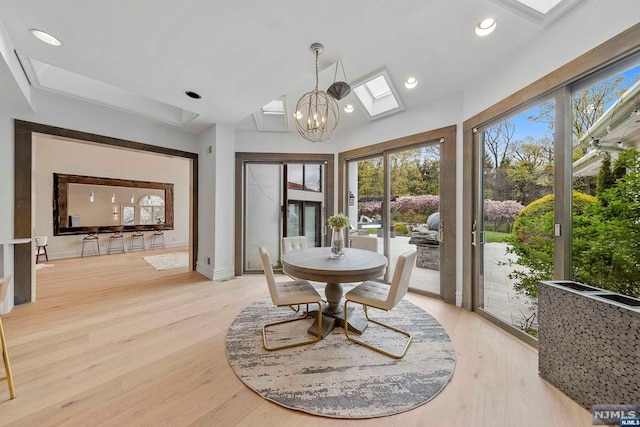 dining space with an inviting chandelier, a skylight, and light hardwood / wood-style flooring