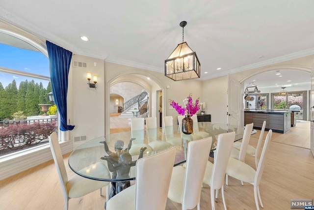 dining room featuring a notable chandelier, a healthy amount of sunlight, ornamental molding, and light hardwood / wood-style flooring