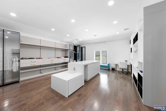 kitchen with hardwood / wood-style floors, white cabinetry, and a kitchen island with sink