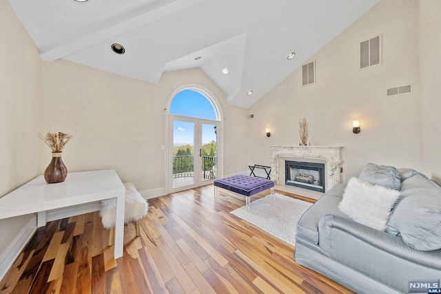 living room with high vaulted ceiling, french doors, light wood-type flooring, a premium fireplace, and beam ceiling