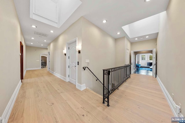 hallway with a skylight and light hardwood / wood-style floors