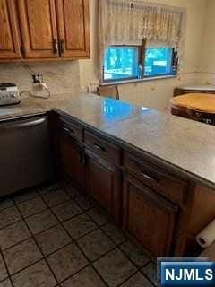 kitchen with stainless steel dishwasher and dark tile patterned flooring