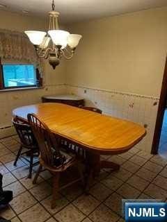 unfurnished dining area featuring tile patterned flooring and an inviting chandelier