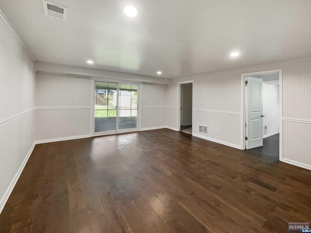 unfurnished room with dark hardwood / wood-style flooring and wooden walls