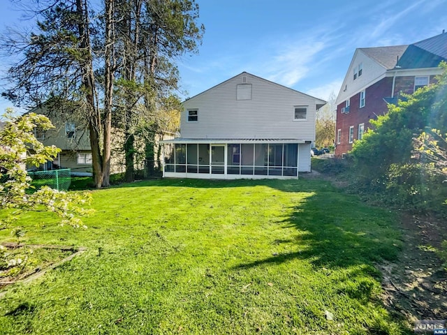 rear view of property with a lawn and a sunroom