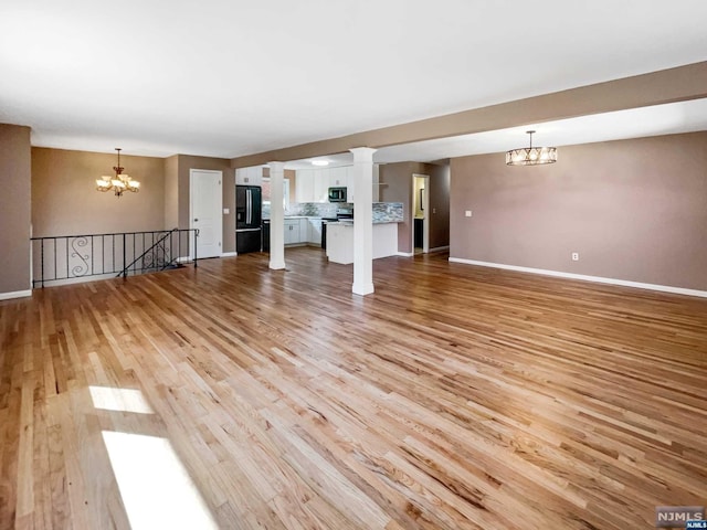 unfurnished living room with a notable chandelier and light hardwood / wood-style floors