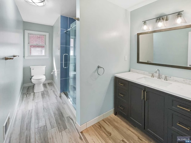 bathroom with vanity, wood-type flooring, an enclosed shower, and toilet