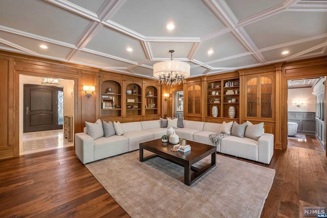 living room with an inviting chandelier, wood walls, dark hardwood / wood-style flooring, and coffered ceiling