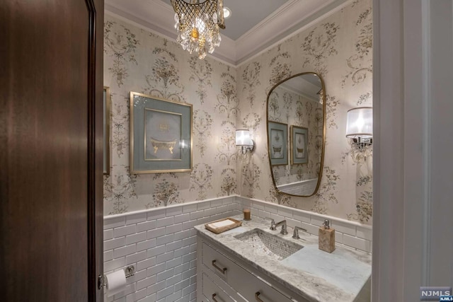 bathroom with a notable chandelier, vanity, crown molding, and tile walls