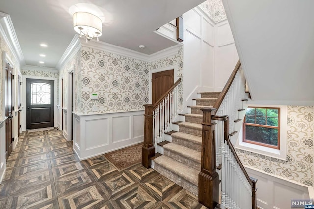 foyer with dark parquet flooring and crown molding