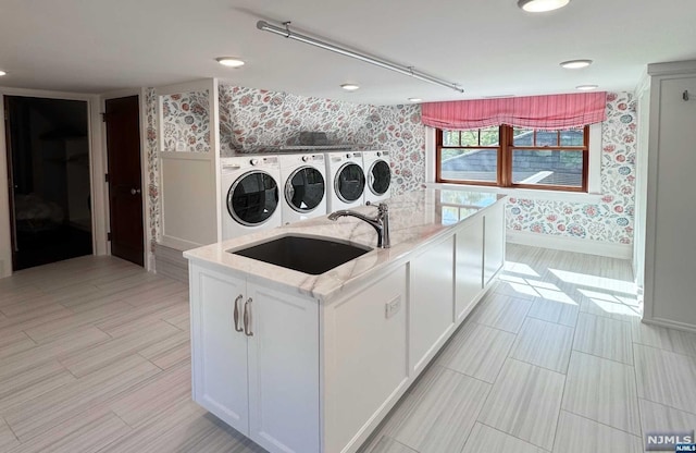 laundry room with light wood-type flooring, sink, and washing machine and clothes dryer