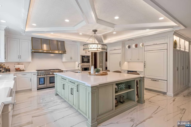 kitchen with pendant lighting, wall chimney exhaust hood, an island with sink, white cabinetry, and stainless steel appliances