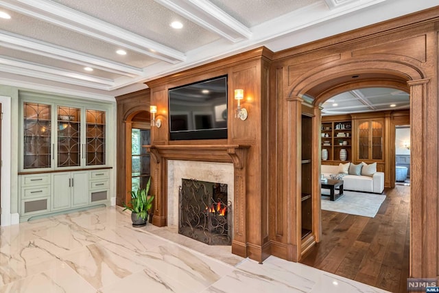 living room featuring a high end fireplace, hardwood / wood-style floors, ornamental molding, and beamed ceiling