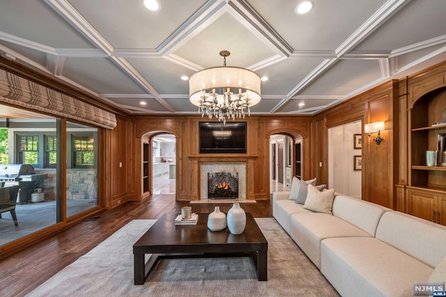 living room featuring wood walls, a notable chandelier, coffered ceiling, and hardwood / wood-style flooring