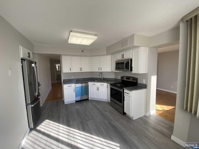 kitchen with white cabinets, appliances with stainless steel finishes, dark hardwood / wood-style flooring, and sink