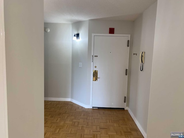 corridor with a textured ceiling and light parquet floors