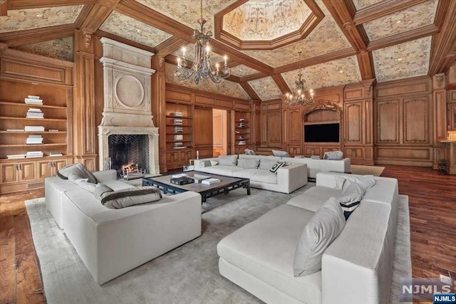 living room with a fireplace, wood-type flooring, built in shelves, and a notable chandelier