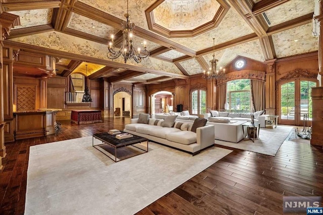 living room with wood walls, decorative columns, dark wood-type flooring, and a chandelier