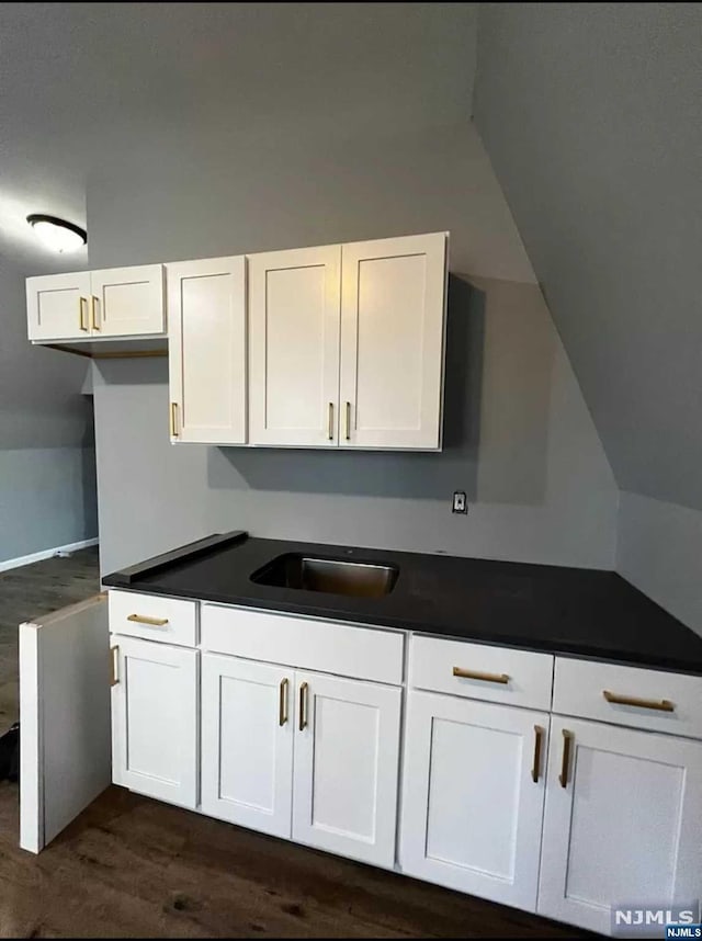 kitchen with sink, white cabinetry, and dark wood-type flooring