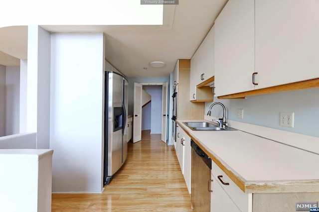 kitchen with light hardwood / wood-style floors, white cabinetry, sink, and appliances with stainless steel finishes