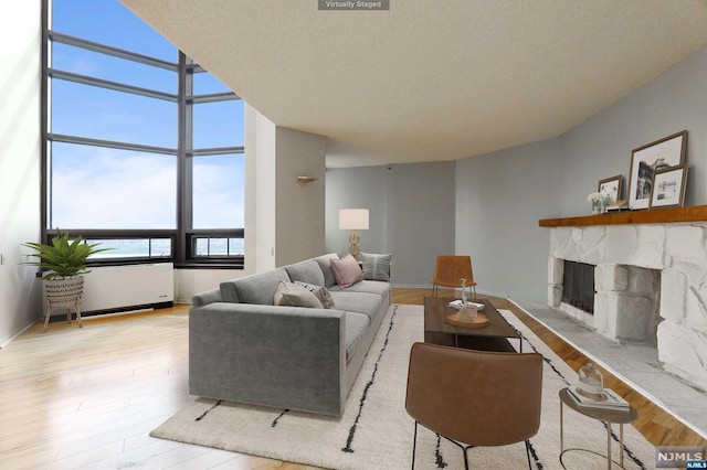 living room featuring a fireplace, a textured ceiling, and light hardwood / wood-style flooring