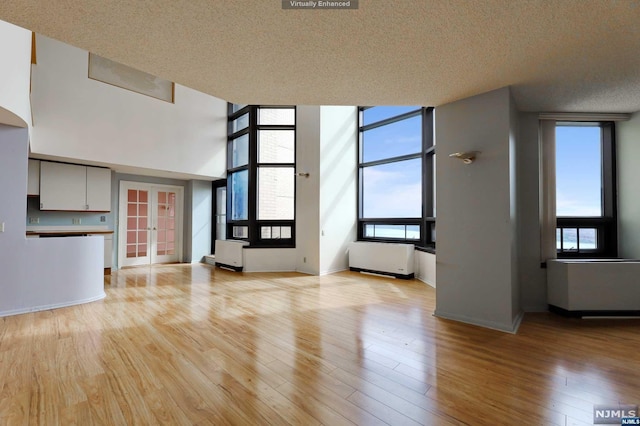 unfurnished living room with french doors, a textured ceiling, and light hardwood / wood-style flooring