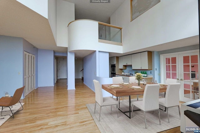 dining room featuring french doors, sink, a high ceiling, and light hardwood / wood-style flooring