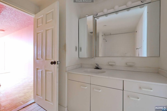 bathroom featuring a textured ceiling, vanity, and parquet floors