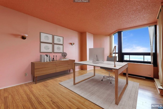 home office featuring a textured ceiling and light hardwood / wood-style flooring